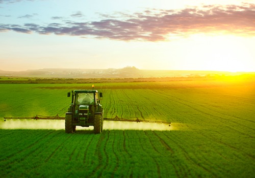 A tractor using Custom Farm Sprayers to fertilize crops